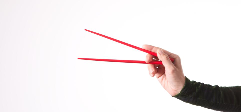 a hand holding a set of chopsticks