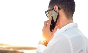 man speaking on the phone as the sun rises behind him