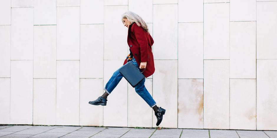 Older professional woman jumping in the air