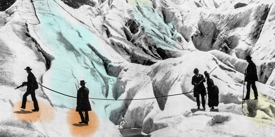 A vintage shot of early mountain climbers helping each other cross a crevasse