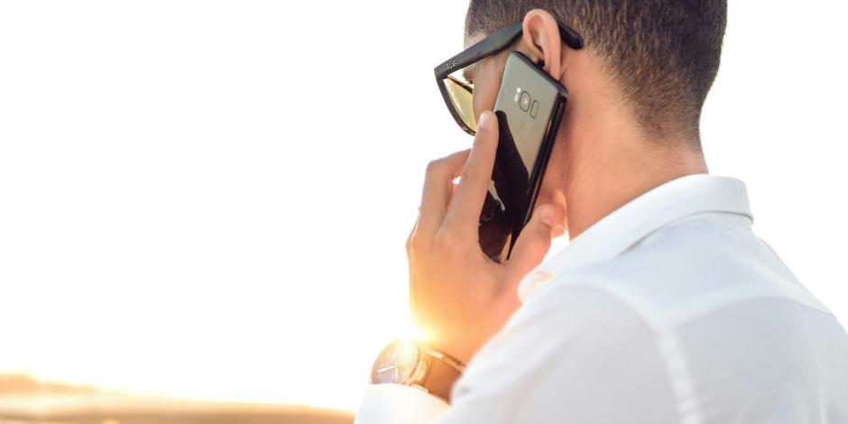 man speaking on the phone as the sun rises behind him