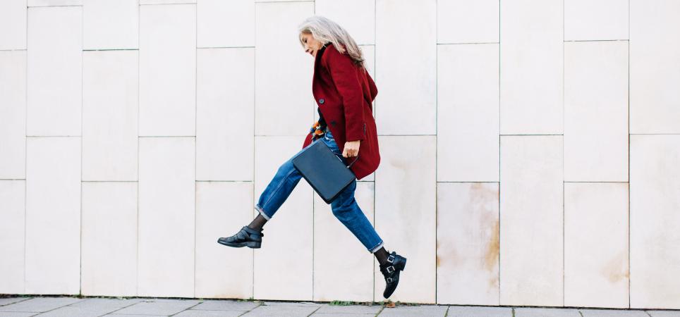 Older professional woman jumping in the air