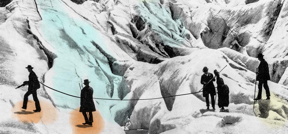 A vintage shot of early mountain climbers helping each other cross a crevasse