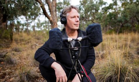 Andrew Skeoch crouched down next to his equipment in the field