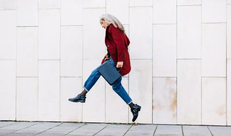 Older professional woman jumping in the air